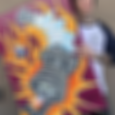 Mike Metzger holding his art of a vibrant painting of a spark plug surrounded by flames and a winged eyeball.