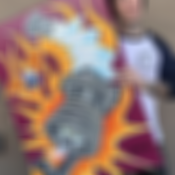 Mike Metzger holding his art of a vibrant painting of a spark plug surrounded by flames and a winged eyeball.