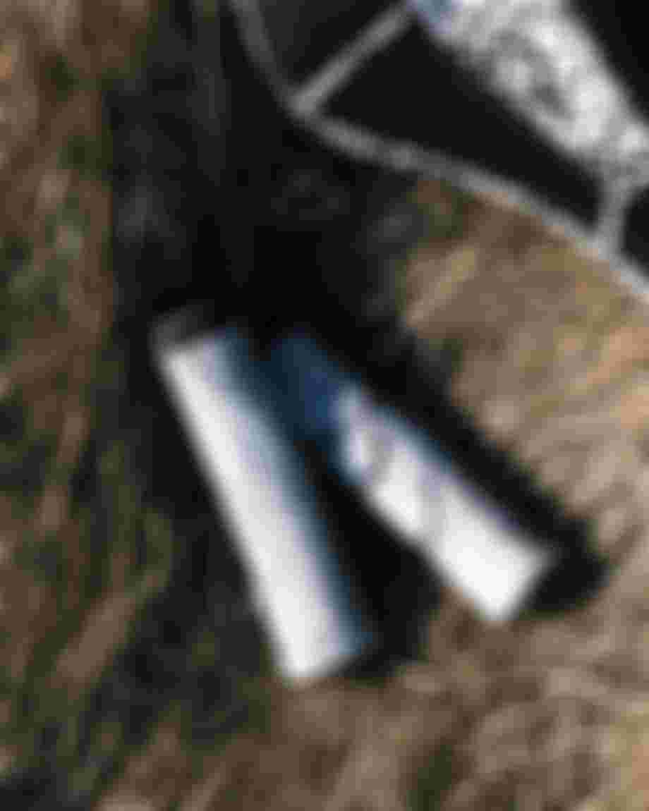 Black and white patterned bicycle seat and two textured bicycle grips on dry grass.