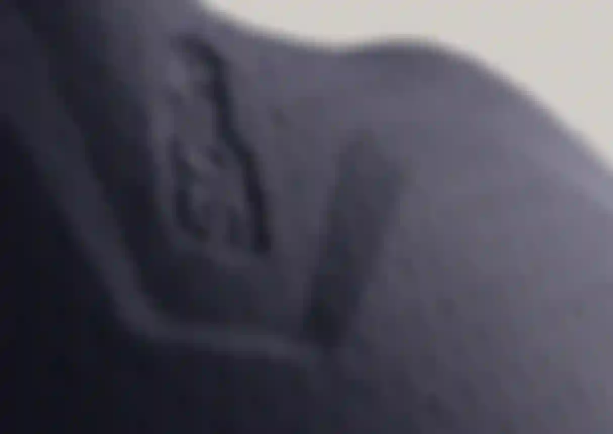 Close-up of dark blue textured fabric with embossed logo, featuring a subtle design and smooth surface.