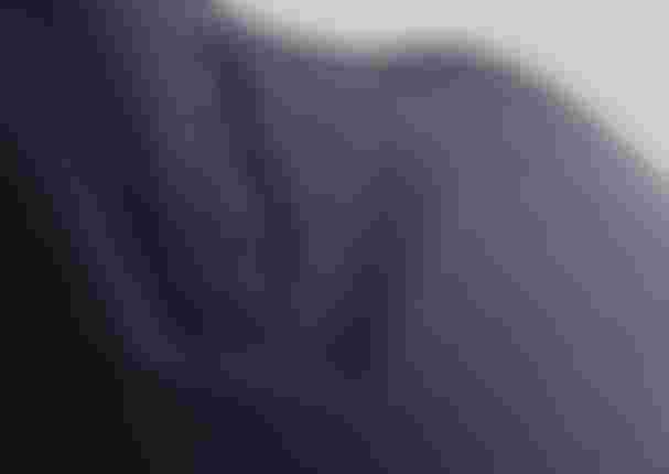 Close-up of dark blue textured fabric with embossed logo, featuring a subtle design and smooth surface.