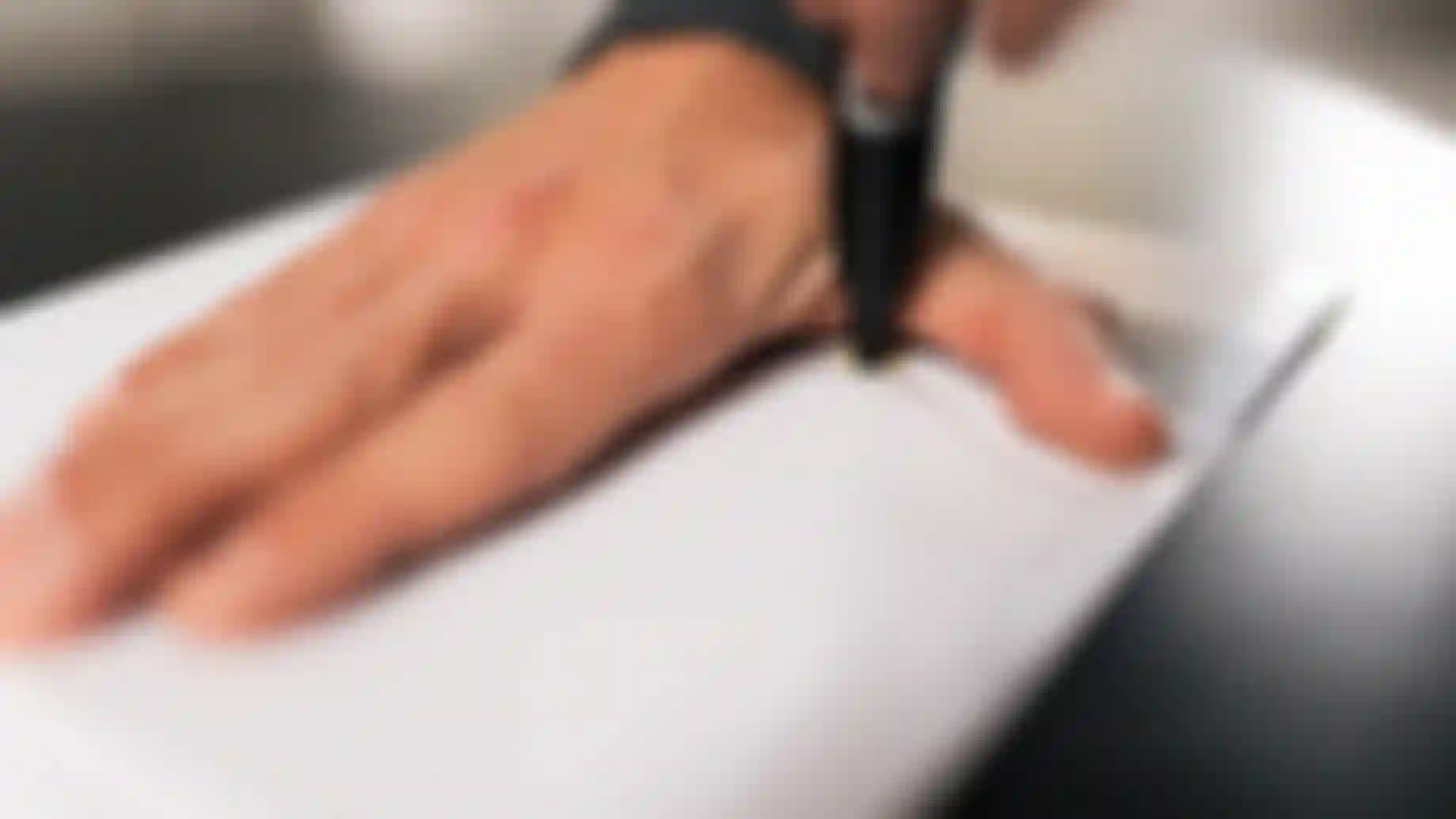 Hand measurement in progress: a hand placed flat on paper while its outline is traced with a pen to determine the correct grip size.