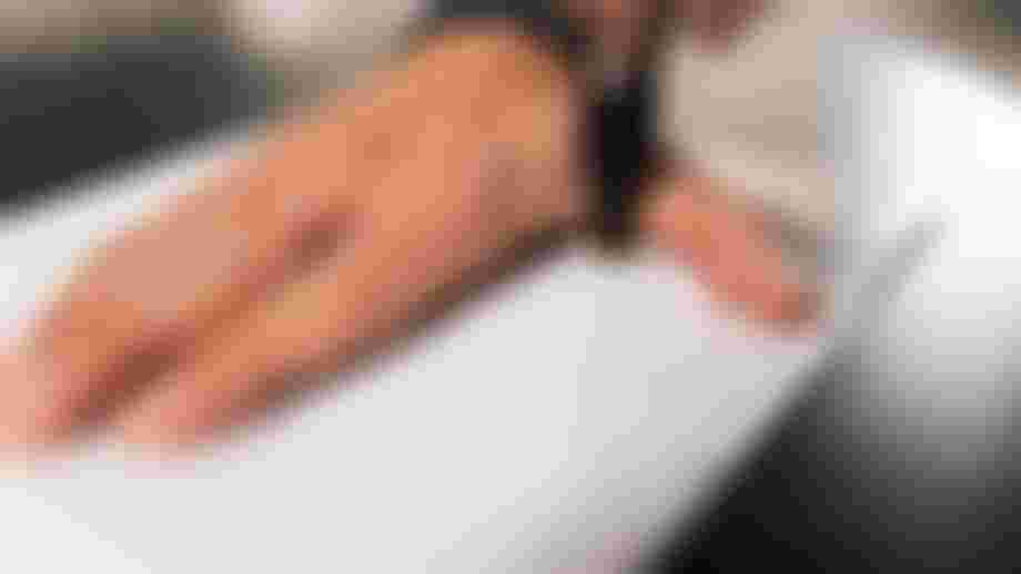 Hand measurement in progress: a hand placed flat on paper while its outline is traced with a pen to determine the correct grip size.