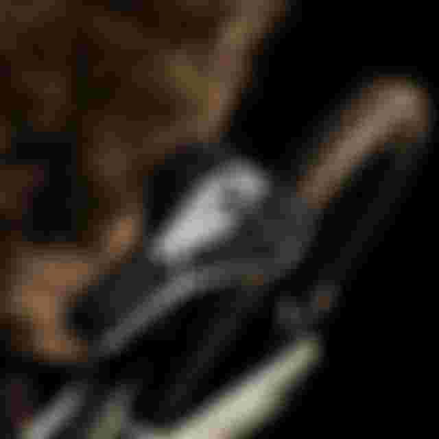 Close-up of a mountain bike seat with a black and white pattern, and a rear knobby tire, set against a dark blurred background.