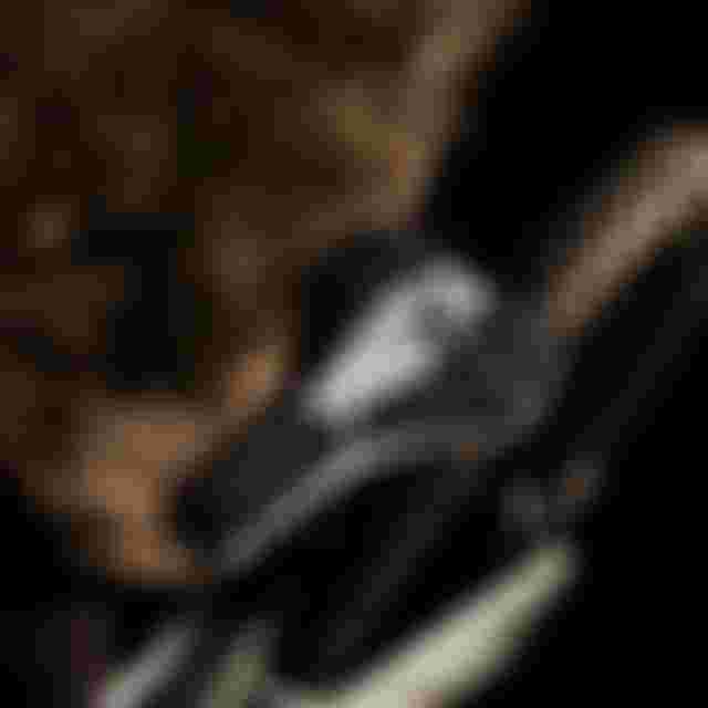 Close-up of a mountain bike seat with a black and white pattern, and a rear knobby tire, set against a dark blurred background.