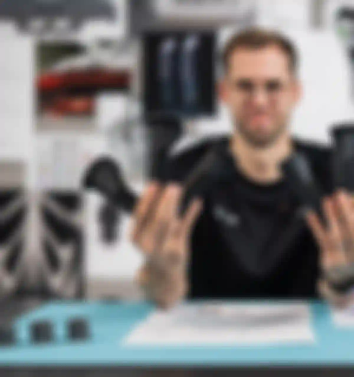 Product developer holding multiple SQlab ergonomic bike grip prototypes in both hands at a design workspace with technical drawings and components.