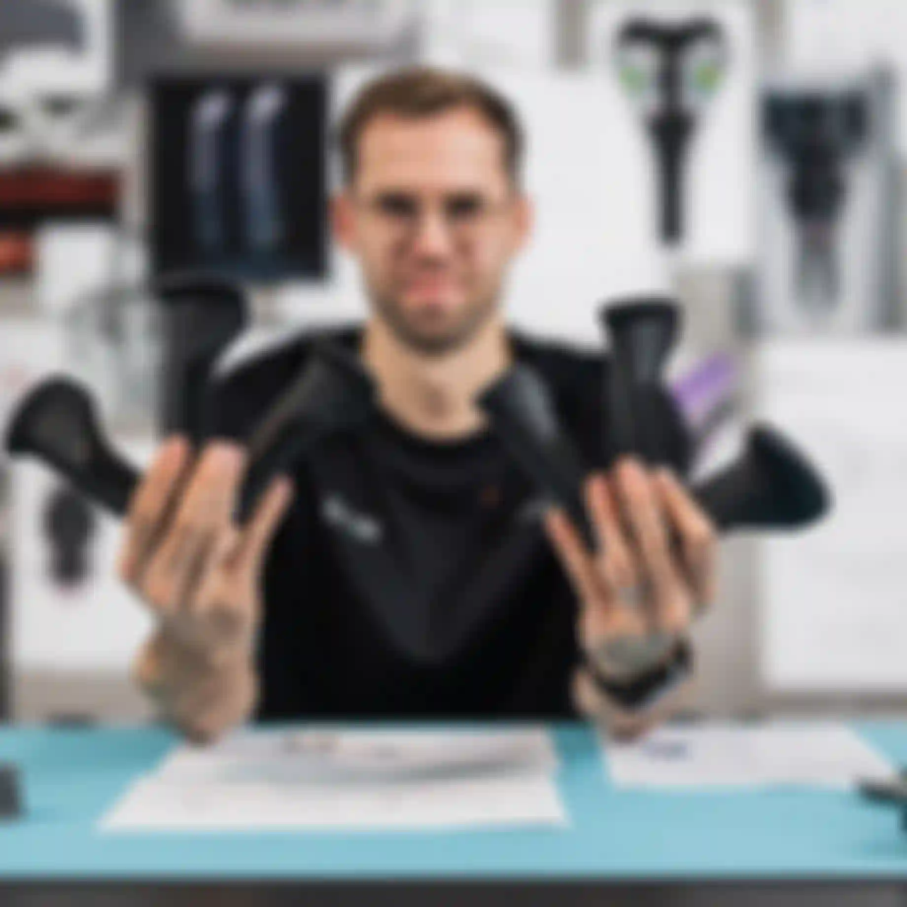 Product developer holding multiple SQlab ergonomic bike grip prototypes in both hands at a design workspace with technical drawings and components.