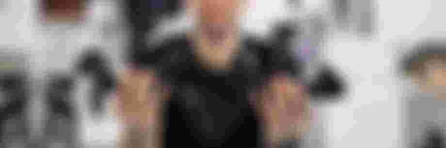 Product developer holding multiple SQlab ergonomic bike grip prototypes in both hands at a design workspace with technical drawings and components.