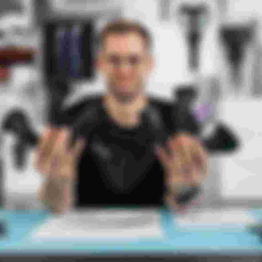 Product developer holding multiple SQlab ergonomic bike grip prototypes in both hands at a design workspace with technical drawings and components.