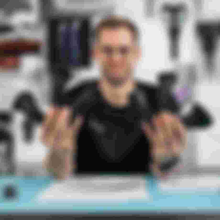 Product developer holding multiple SQlab ergonomic bike grip prototypes in both hands at a design workspace with technical drawings and components.