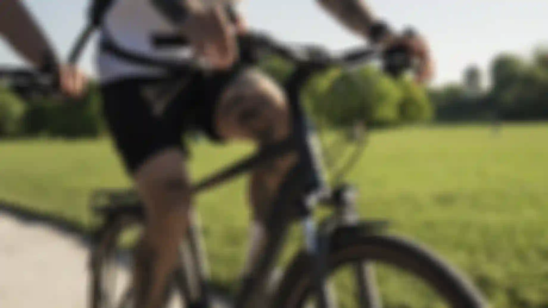 Close-up of a tattooed person riding a bicycle on a sunny day, with a lush green park in the background.
