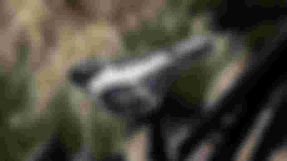 Close-up of a bicycle saddle with a black and white camouflage pattern, attached to the bike post, with blurred outdoor background.