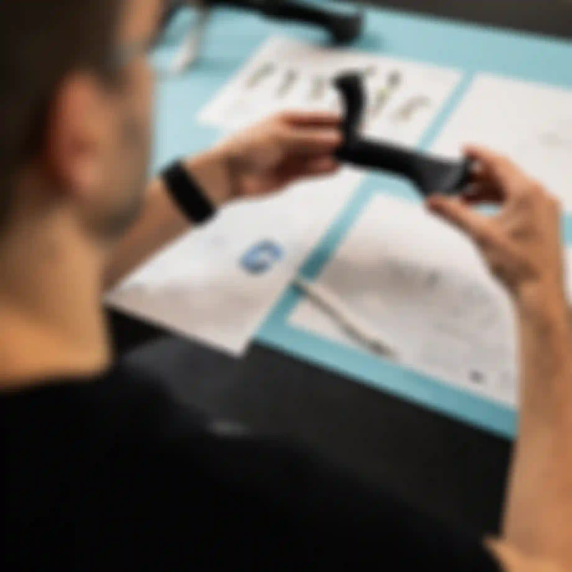 Top view of hands holding a SQlab ergonomic bicycle grip prototype over technical design drawings on a workbench.