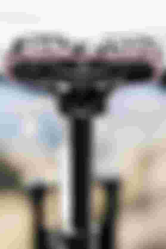 Close-up of a bicycle saddle with a black and white pattern, on a blurred outdoor background.