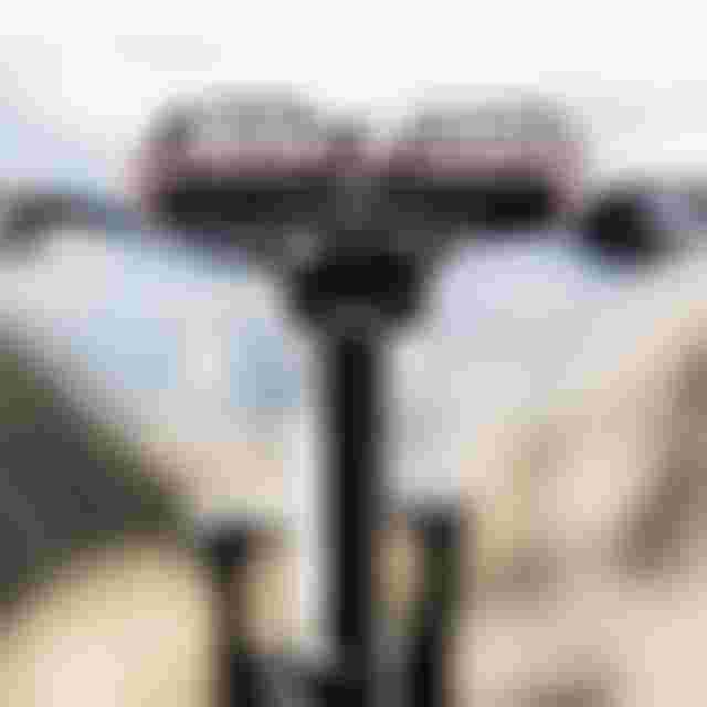 Close-up of a bicycle saddle with a black and white pattern, on a blurred outdoor background.