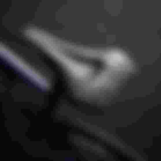 Close-up of a sleek black bicycle saddle with ergonomic design, mounted on a bike against a blurred dark background.