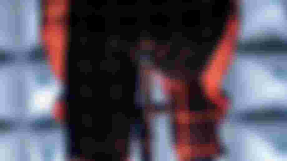 Close-up view of cyclist wearing a grid-patterned suit, from behind on a bike, with dynamic lighting highlighting the outfit.