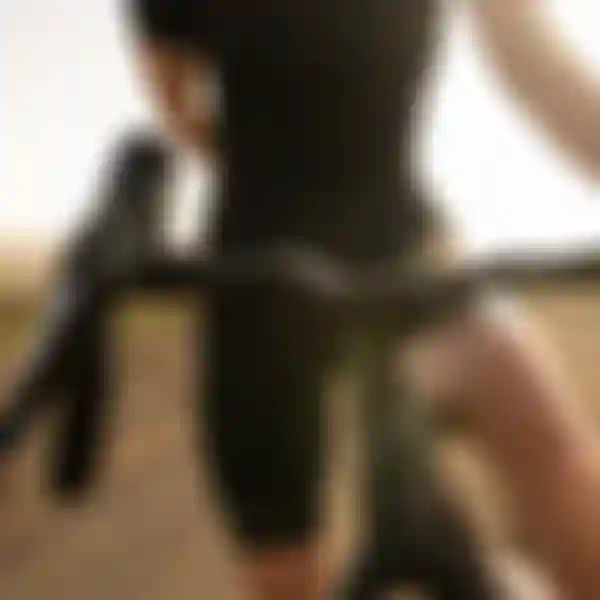 A person wearing a black outfit holding the handlebars of a bicycle on a sunlit dirt road.