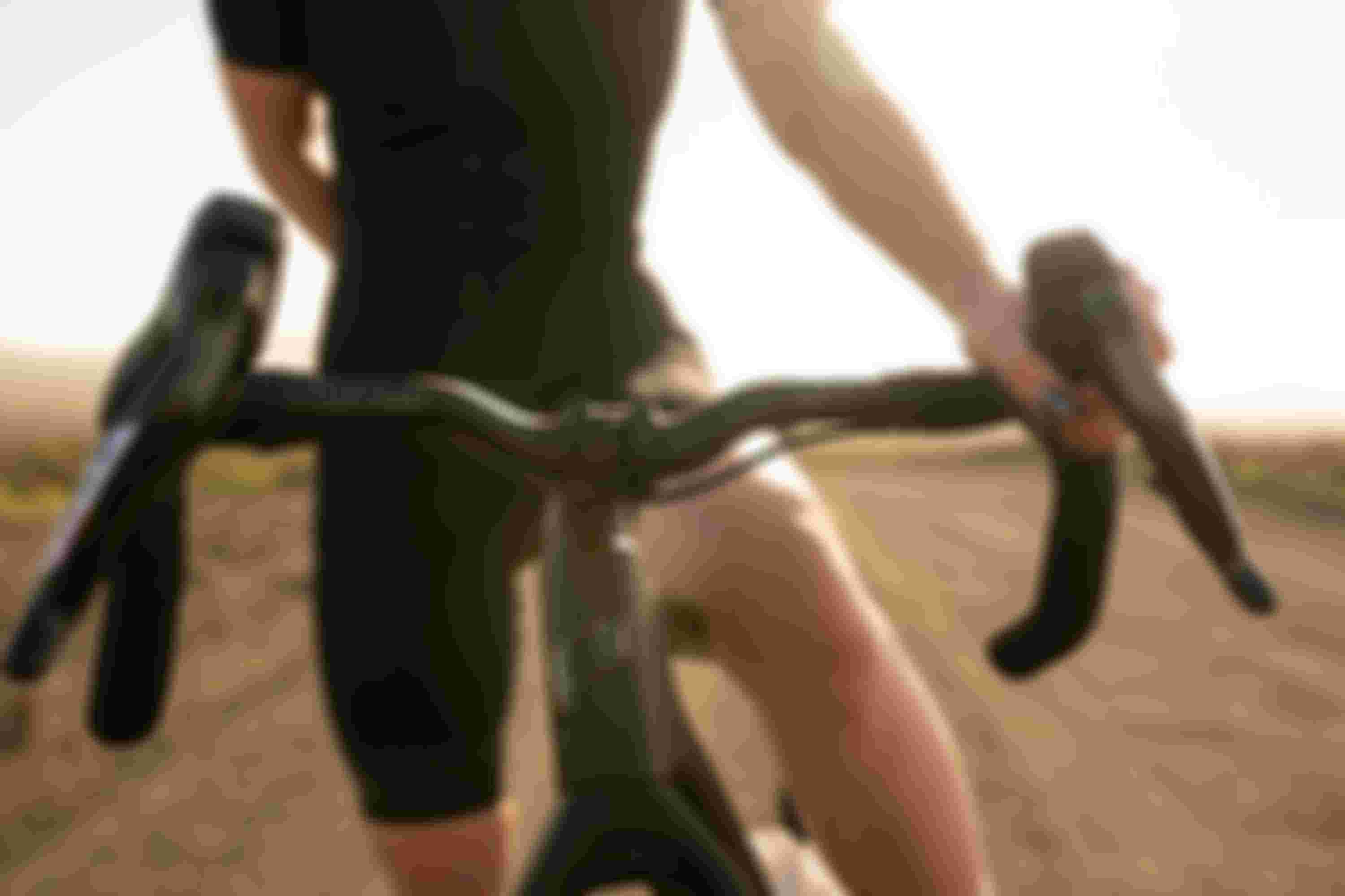 A person wearing a black outfit holding the handlebars of a bicycle on a sunlit dirt road.