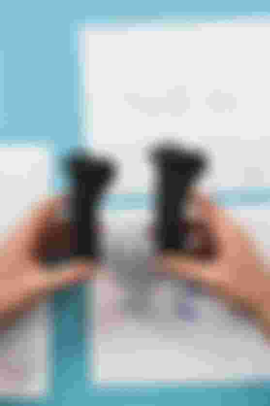 Overhead view of hands holding two SQlab ergonomic bike grips above technical drawings on a cutting mat during product development.