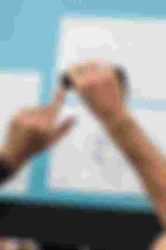 Top view of hands measuring a SQlab 702 2.0 ergonomic trekking bike grip on a design workspace with technical drawings.