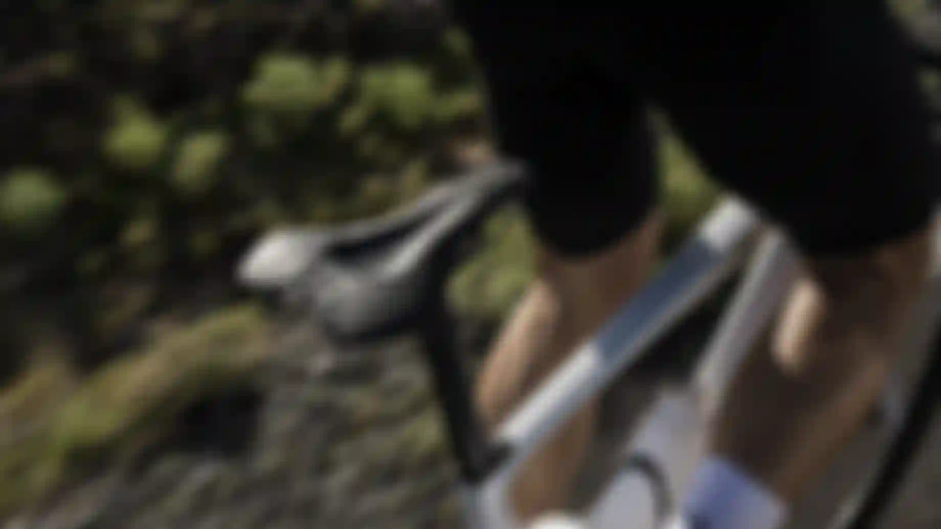 Cyclist in black shorts riding a white bicycle on a blurred outdoor path, emphasizing the bike seat and rider's leg muscles.
