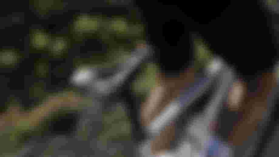 Cyclist in black shorts riding a white bicycle on a blurred outdoor path, emphasizing the bike seat and rider's leg muscles.