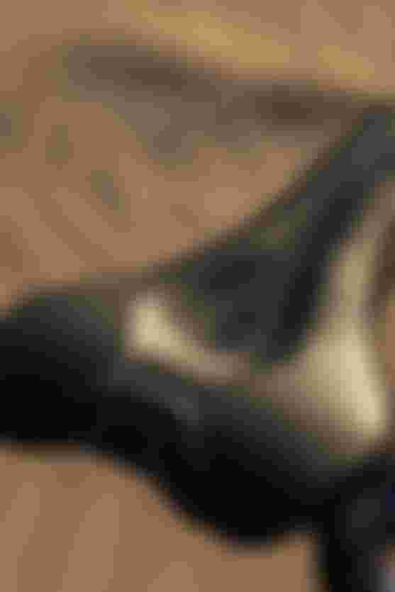 Close-up of a black bicycle saddle with "6012" and "5014G" markings, set against a blurred sandy background.