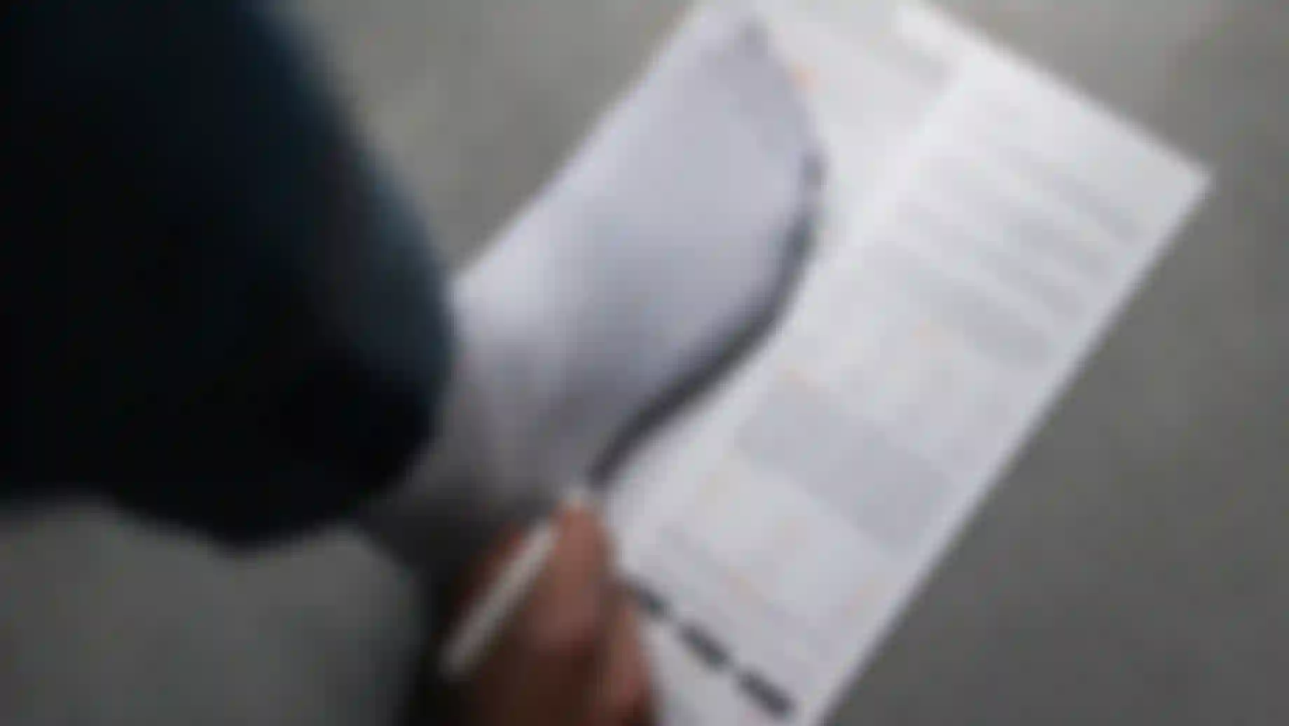 A person wearing a white sock steps on a foot measurement guide, holding a pen, with instructions and diagrams visible.