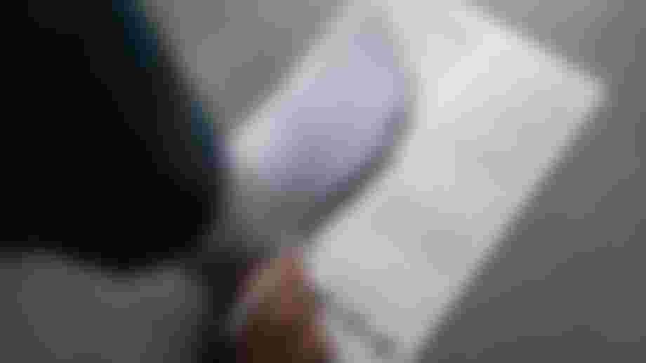 A person wearing a white sock steps on a foot measurement guide, holding a pen, with instructions and diagrams visible.