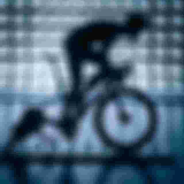Silhouette of a cyclist on a bike in a dark, futuristic room with geometric, backlit walls.