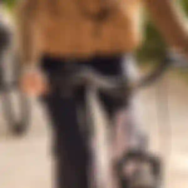 A person in a tan jacket and dark pants rides a purple Scott bike on a sunny path, holding the handlebars firmly.