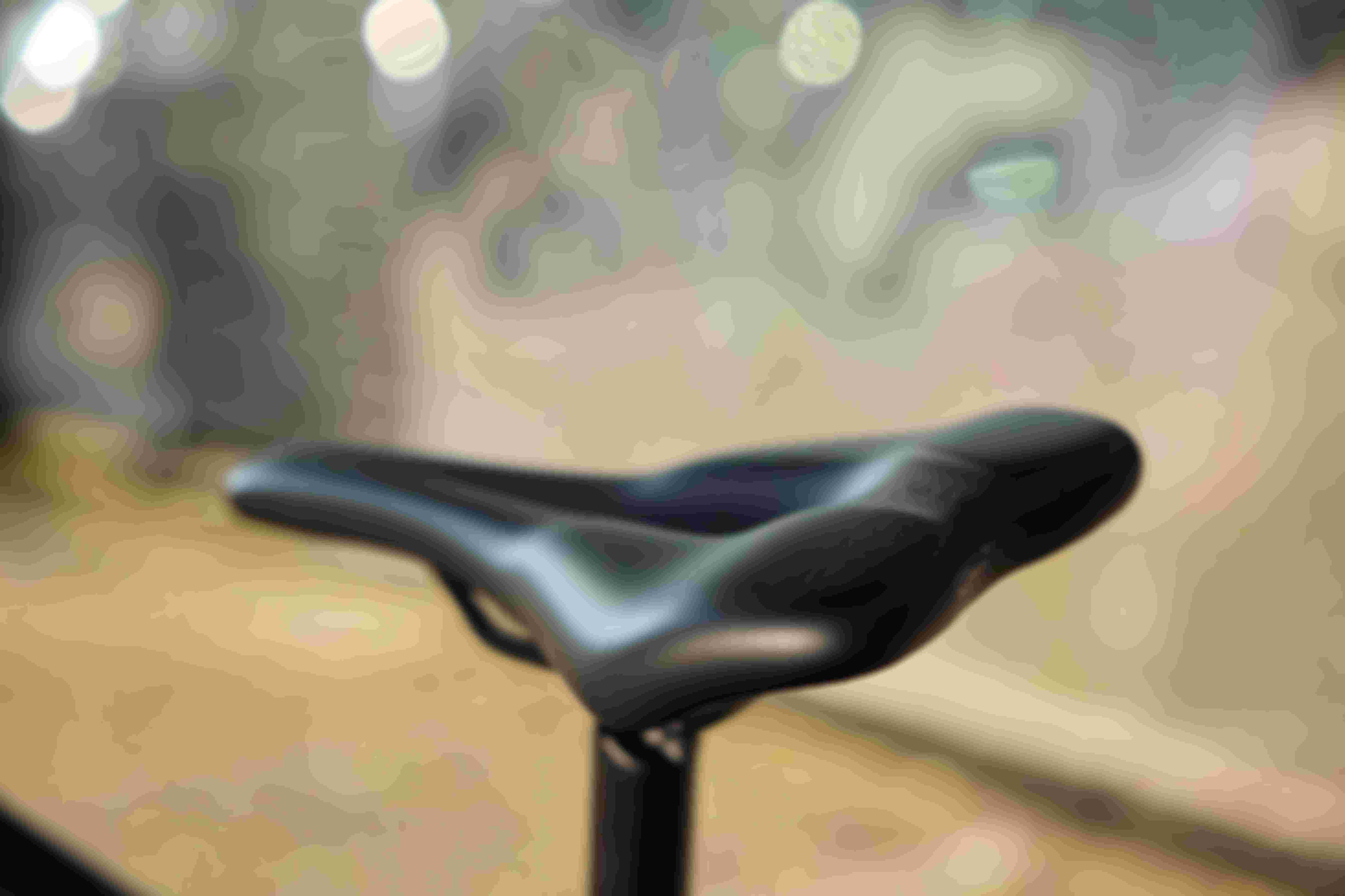 Close-up of a sleek black SQlab bicycle saddle with blurred lights in the background.