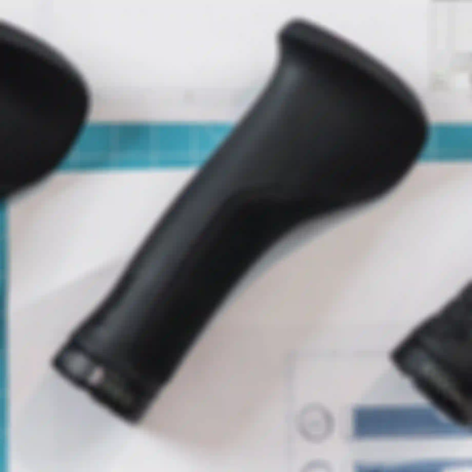 Black ergonomic bike grips on a blueprint background with grid lines and technical drawings.