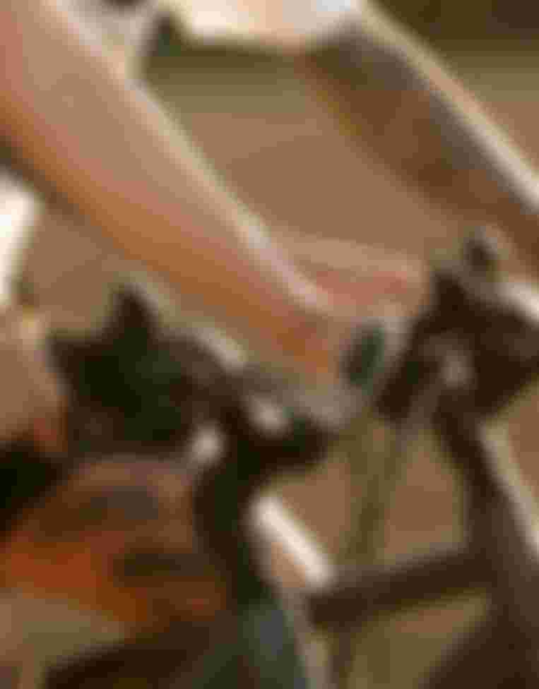 Close-up of two cyclists' tattooed arms gripping the handlebars of their bikes during a ride in soft sunlight.