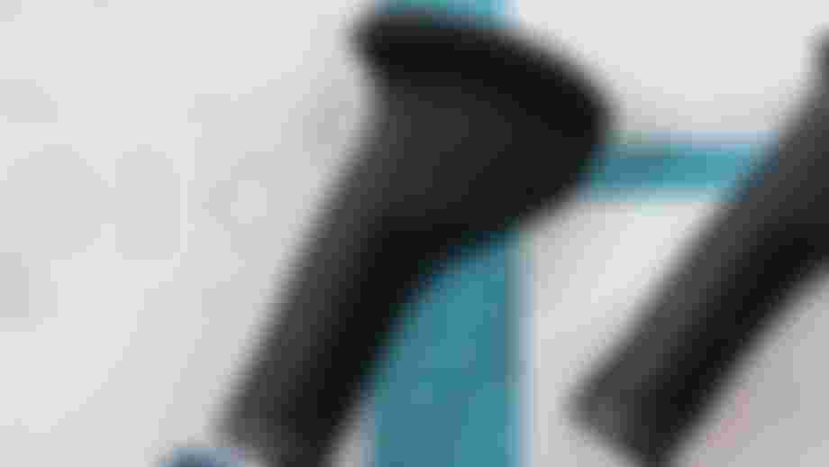 Black ergonomic bicycle grips on a blueprint with a grid cutting mat, showing design and measurements.