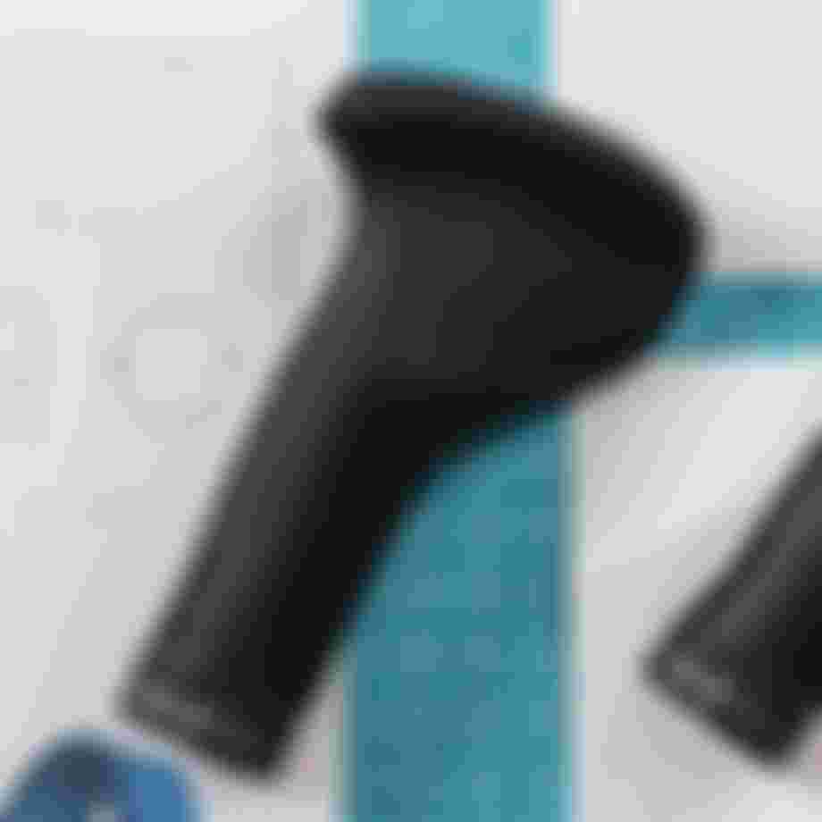 Black ergonomic bicycle grips on a blueprint with a grid cutting mat, showing design and measurements.