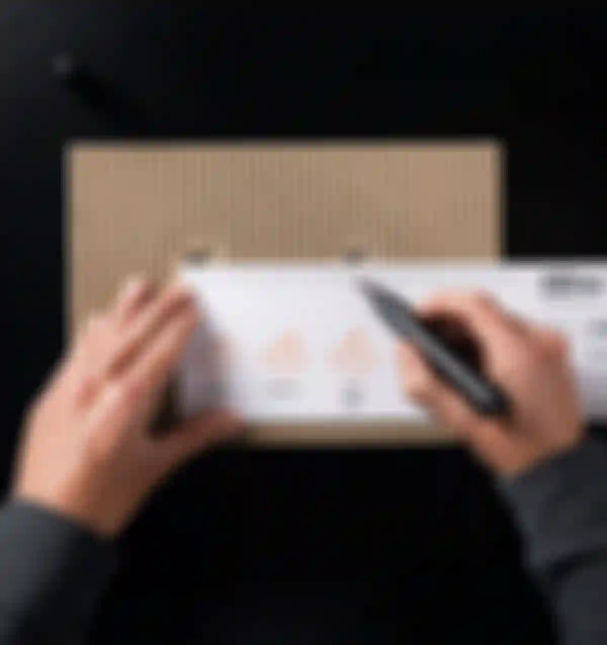A person measures a cardboard piece with a ruler and marker, displaying bicycle drawings and measurements.