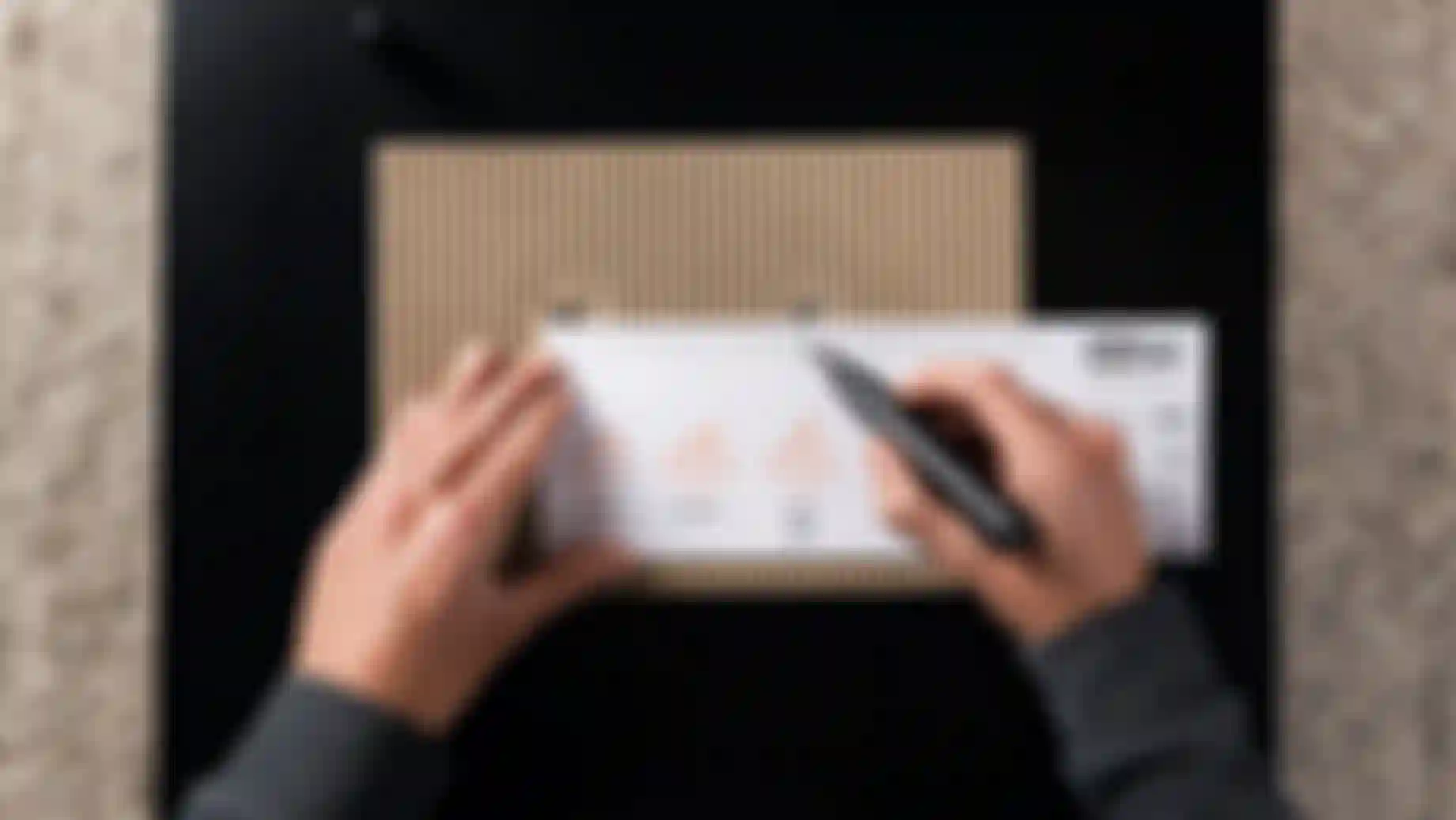 A person measures a cardboard piece with a ruler and marker, displaying bicycle drawings and measurements.