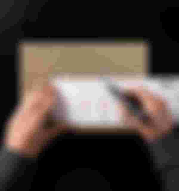 A person measures a cardboard piece with a ruler and marker, displaying bicycle drawings and measurements.