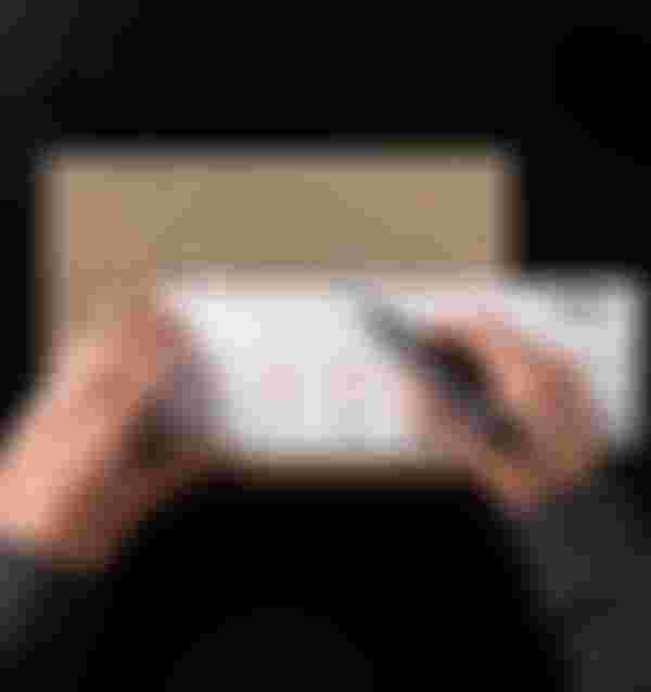 A person measures a cardboard piece with a ruler and marker, displaying bicycle drawings and measurements.