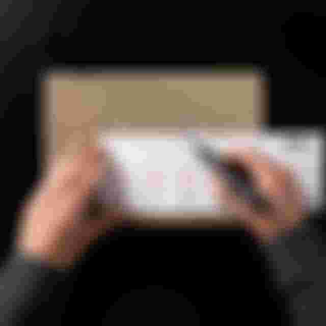 A person measures a cardboard piece with a ruler and marker, displaying bicycle drawings and measurements.