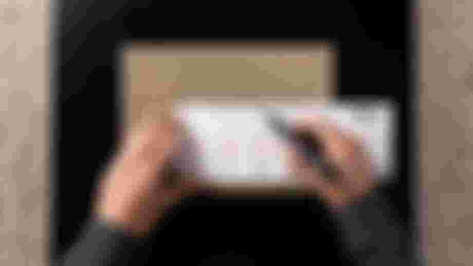 A person measures a cardboard piece with a ruler and marker, displaying bicycle drawings and measurements.