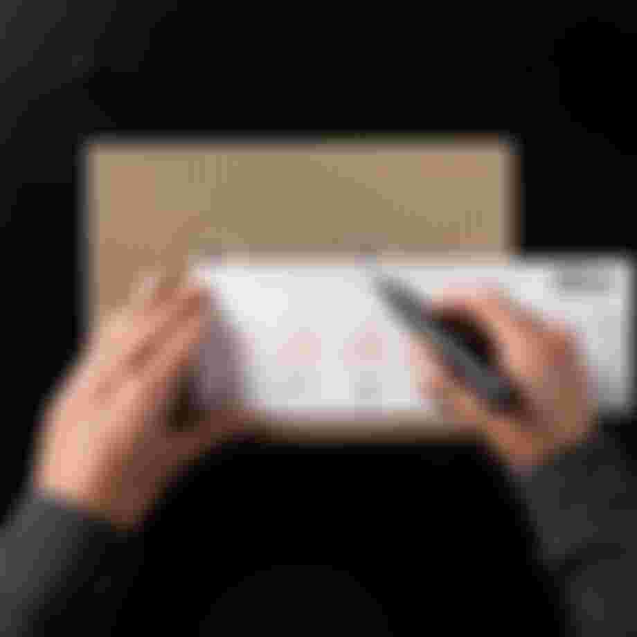 A person measures a cardboard piece with a ruler and marker, displaying bicycle drawings and measurements.