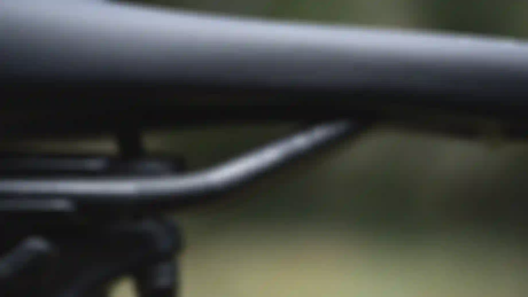 Close-up of a black bike saddle and rails with SQlab branding, photographed against a blurred outdoor background.