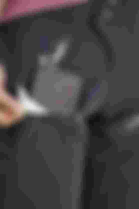 Close-up of MTB pants front pocket with waterproof zipper, showing a smartphone stored securely inside while riding.