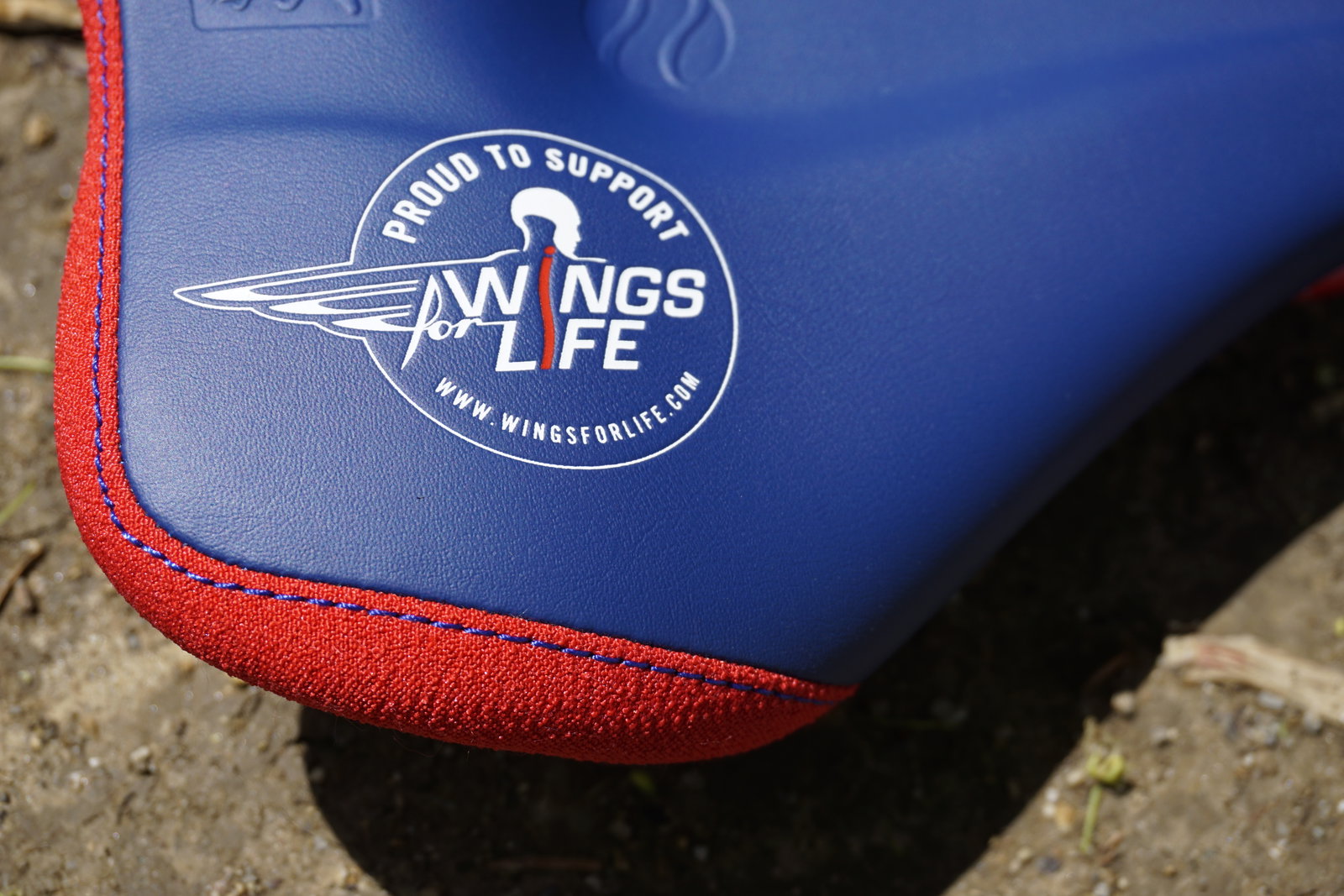 SQlab 611 Ergowave active ltd. Wings for Life saddle in royal blue and red – logo detail