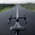 SQlab 612R ERGOWAVE Carbon road saddle in matte black mounted on road bike riding on open asphalt road