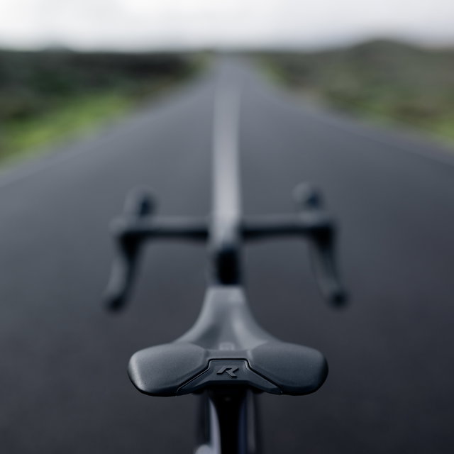 SQlab 612R ERGOWAVE Carbon road saddle in matte black mounted on road bike riding on open asphalt road