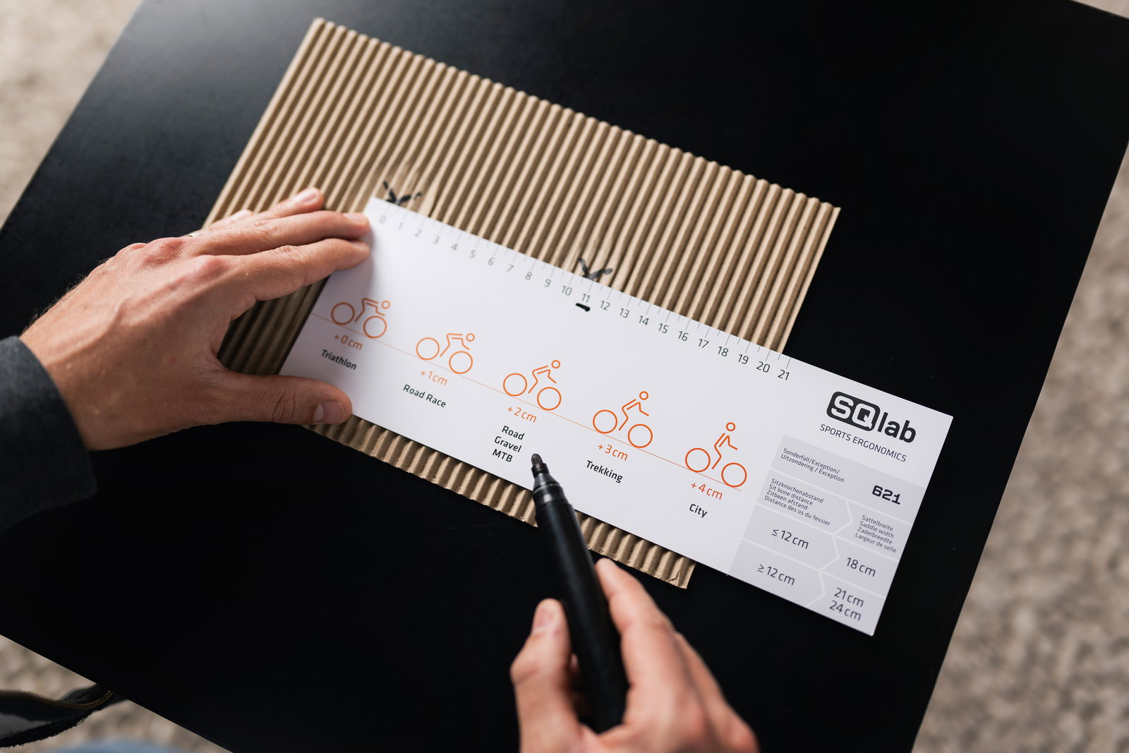 SQlab Measure at Home Set saddle fitting card with discipline guide in use on a desk